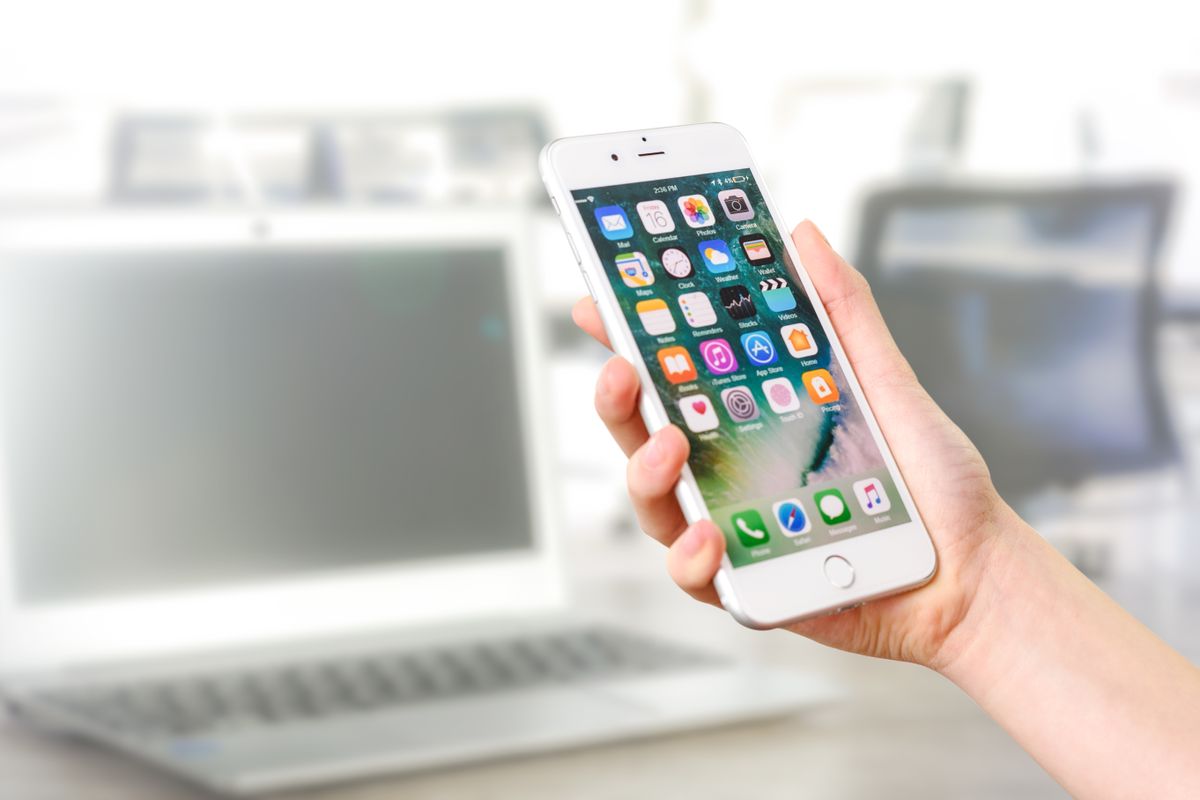 Reviewing a business app on smartphone alongside development work on laptop