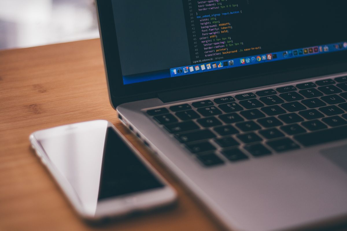 Developer building and testing a mobile application on laptop and smartphone
