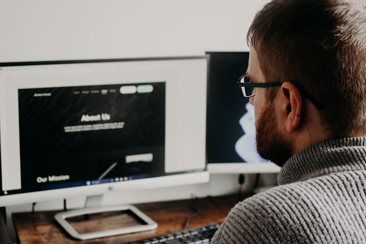 Web developer working on a business website across dual monitors